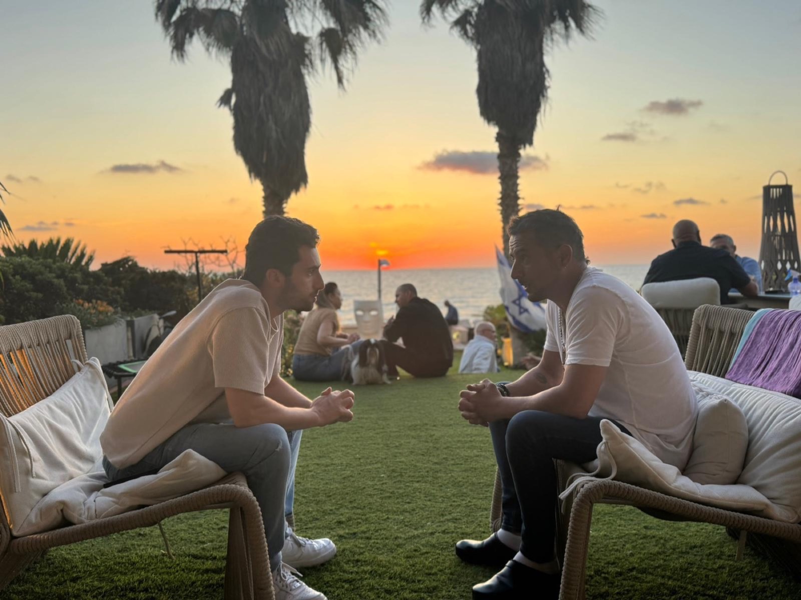 שני אנשים יושבים זה מול זה ומשוחחים בשקיעה